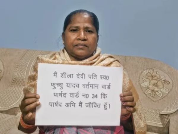 Ward councillor declared dead in Bihar holds “I am alive” poster to protest official error.